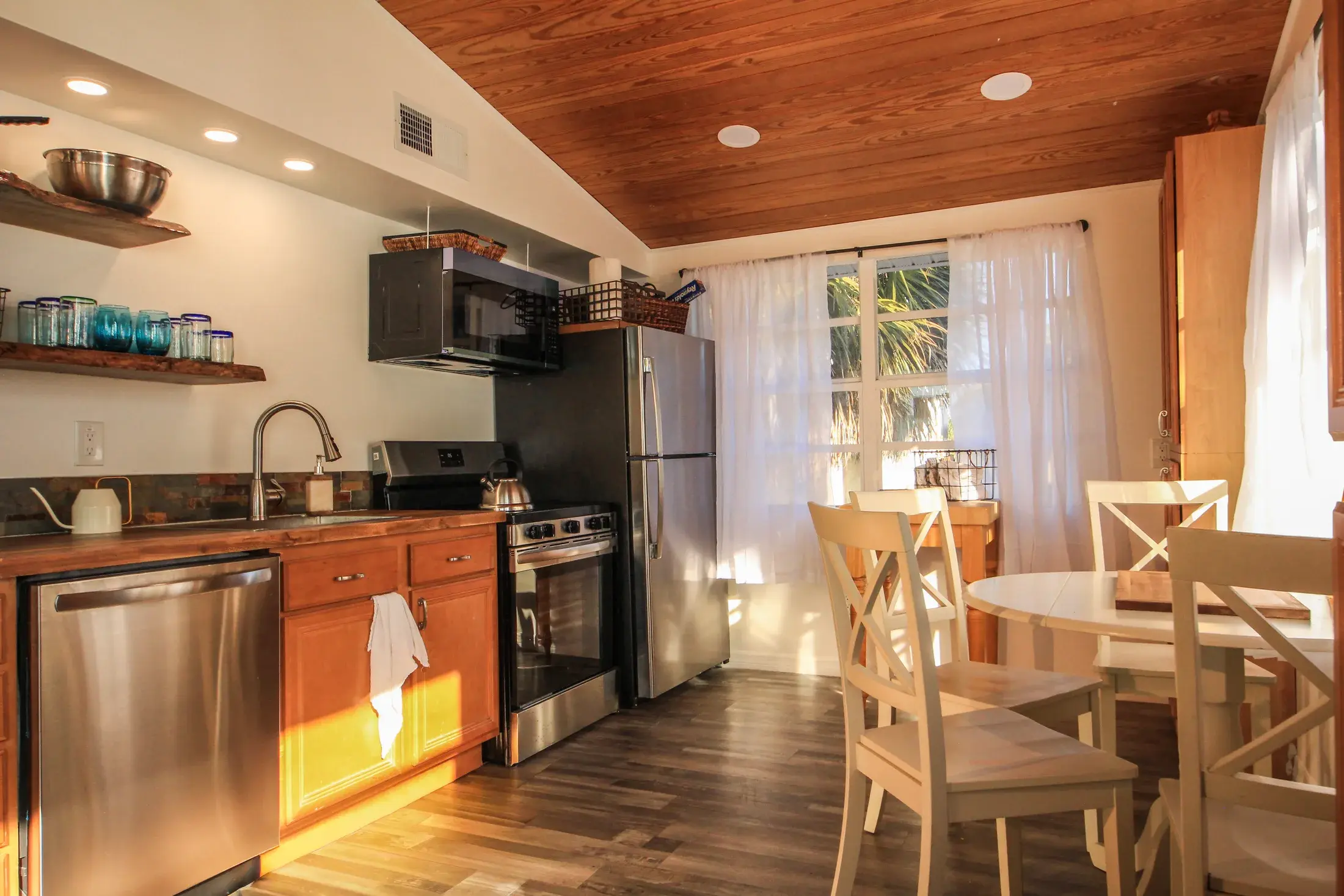 Kitchen and dining area with wood ceilings and natural afternoon light.